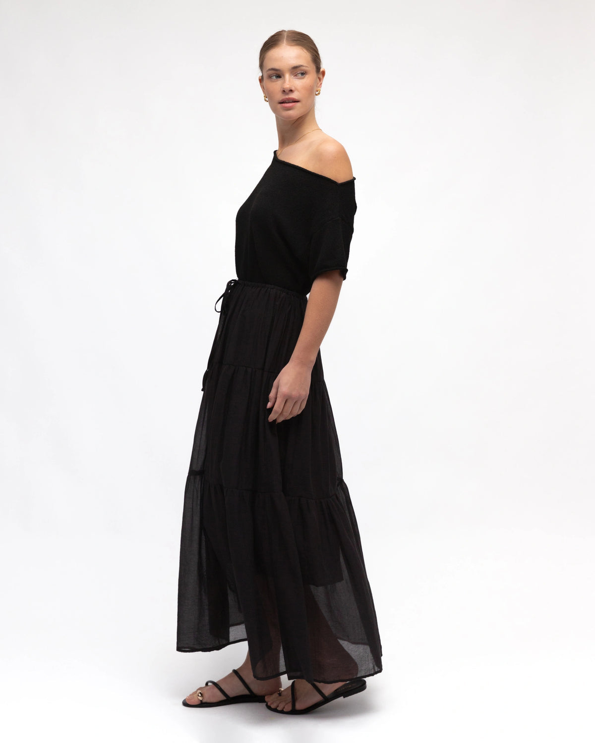 Woman wearing a black off-shoulder top and long skirt on a white background