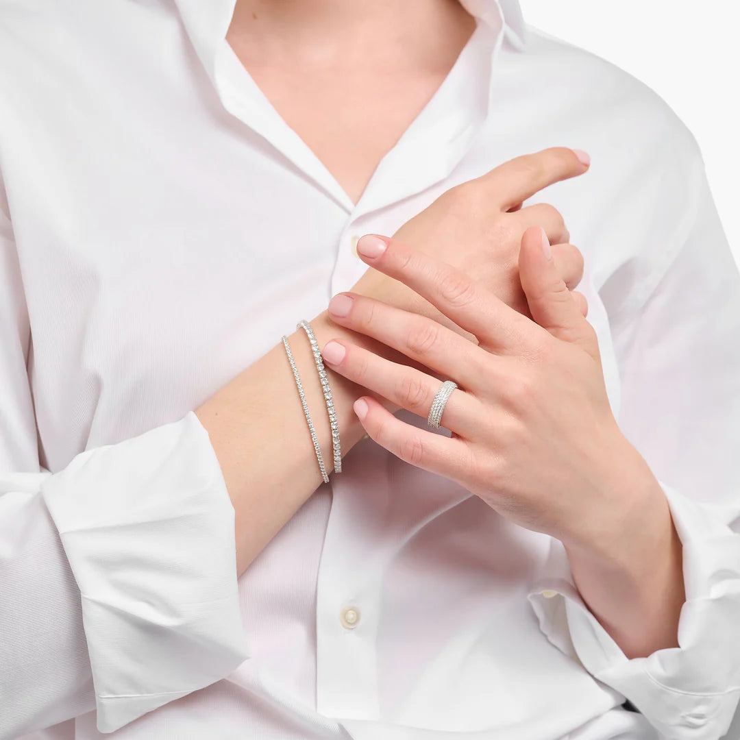 Close-up of a person wearing silver bracelets and rings on a white background